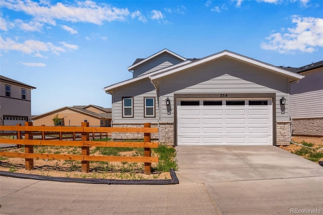 view of front facade featuring a garage, driveway, stone siding, and fence