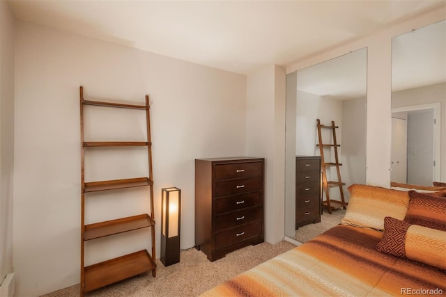 bedroom with light carpet and a baseboard heating unit