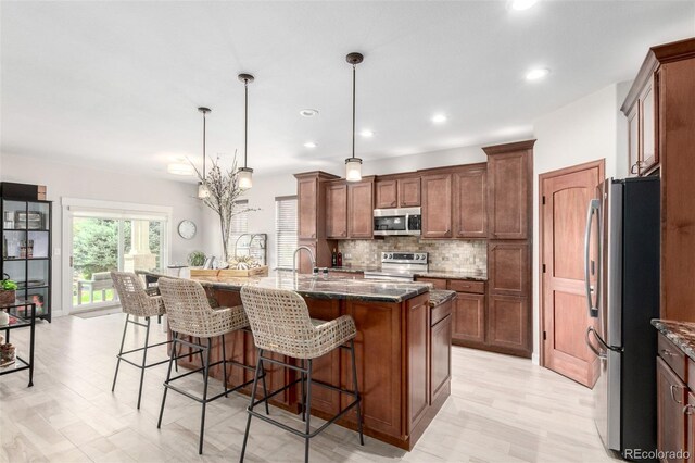 23644 E Phillips Pl, Aurora, CO 80016 - kitchen with dark stone countertops, a breakfast bar area, appliances with stainless steel finishes, and tasteful backsplash