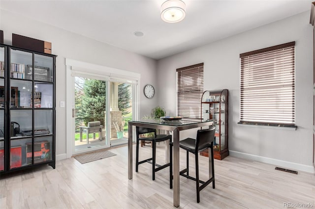 dining space featuring baseboards, light wood-style flooring, and visible vents