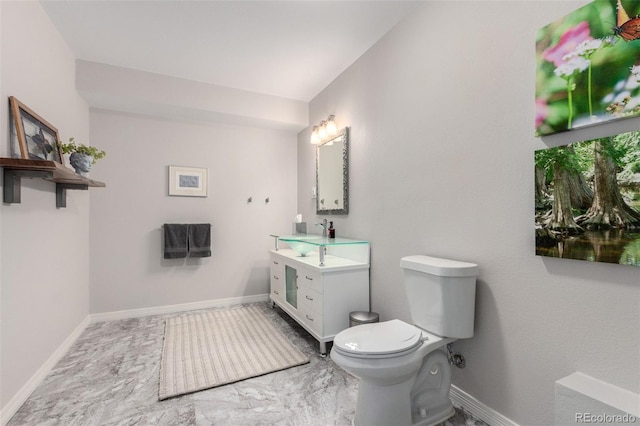half bath with toilet, baseboards, and vanity
