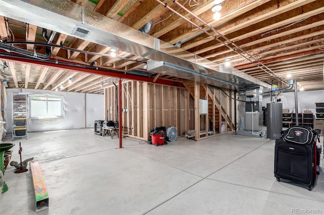 basement with water heater, heating unit, and visible vents