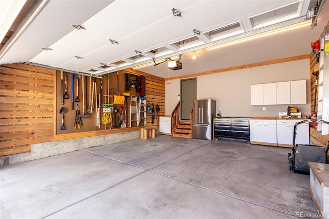 garage with freestanding refrigerator, a workshop area, and a garage door opener