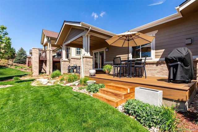 rear view of house featuring a lawn, outdoor dining space, a wooden deck, and brick siding
