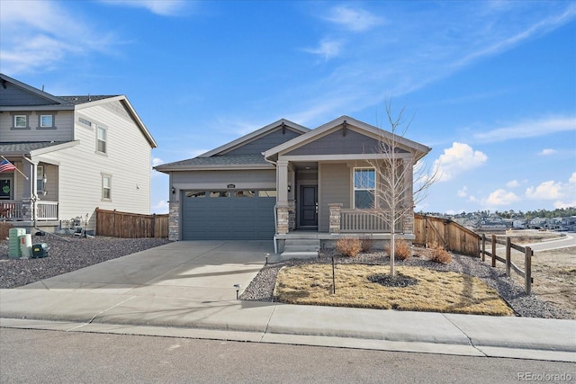 view of front of property featuring fence, concrete driveway, covered porch, stone siding, and an attached garage