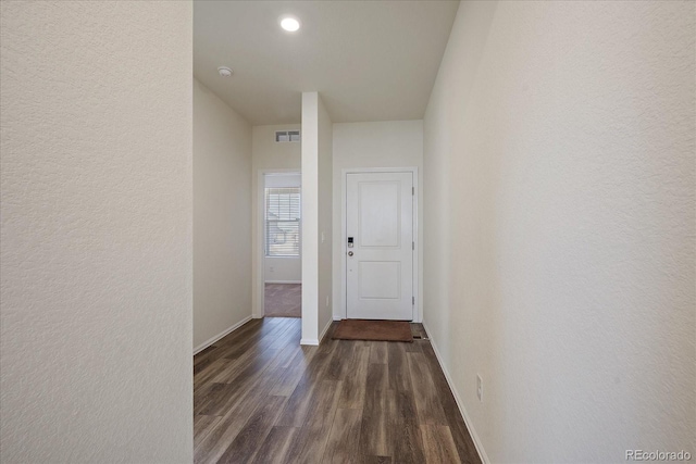 hallway featuring visible vents, baseboards, and dark wood finished floors