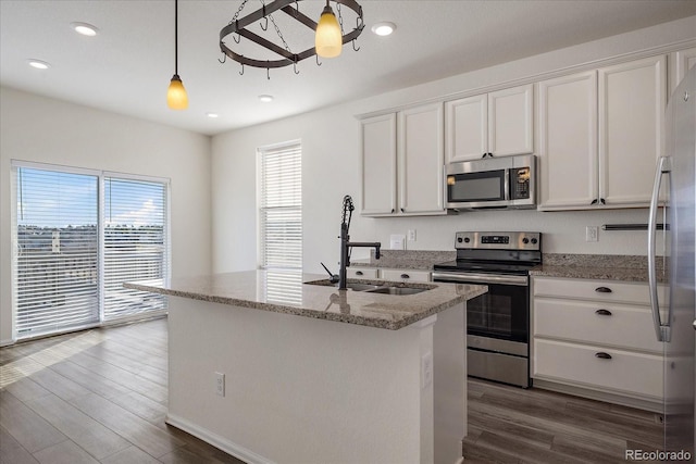 kitchen featuring a sink, stainless steel appliances, light stone counters, and dark wood finished floors