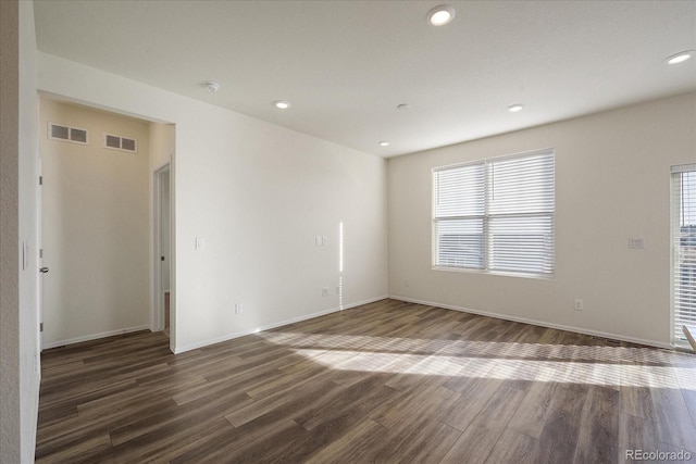 spare room featuring a wealth of natural light, visible vents, and wood finished floors