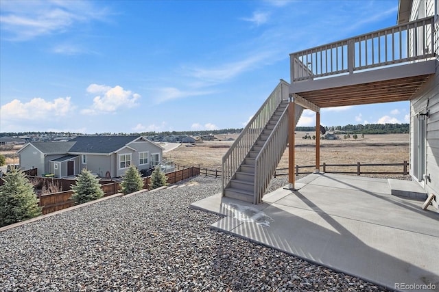 view of yard with a patio area, a wooden deck, stairs, and fence