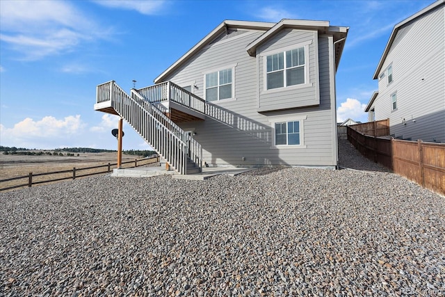 rear view of property featuring a patio area, stairway, fence, and a wooden deck