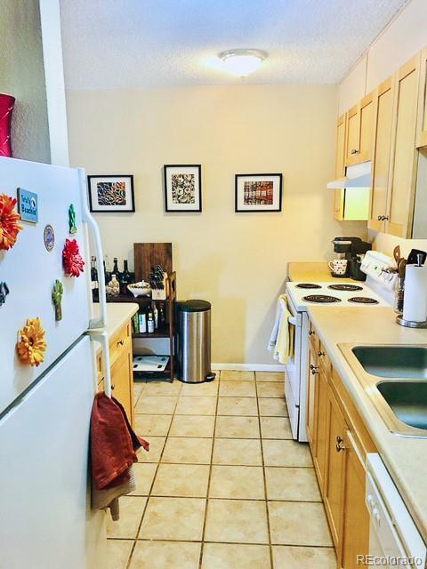 2500 S York St Unit 213, Denver, CO 80210 - kitchen featuring white appliances, light tile patterned floors, under cabinet range hood, light countertops, and a sink