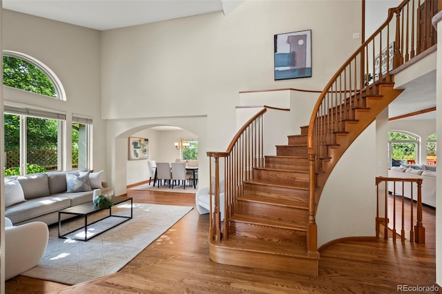 7313 Poston Way, Boulder, CO 80301 - living area featuring arched walkways, a towering ceiling, wood finished floors, and stairway