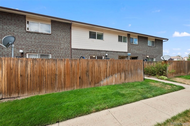 exterior space with brick siding, a lawn, and fence