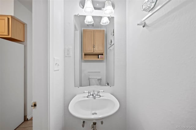 half bathroom featuring tile patterned flooring, a sink, and toilet