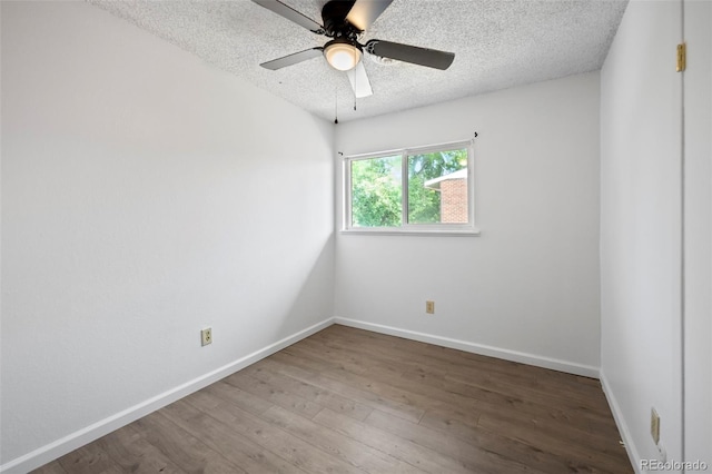 empty room with a ceiling fan, a textured ceiling, baseboards, and wood finished floors