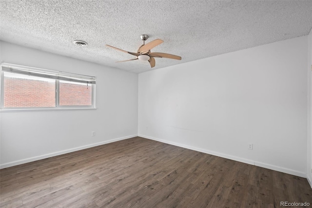 empty room with baseboards, ceiling fan, visible vents, and dark wood-type flooring