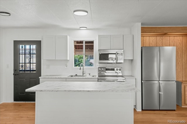 kitchen with light stone counters, sink, white cabinets, and appliances with stainless steel finishes