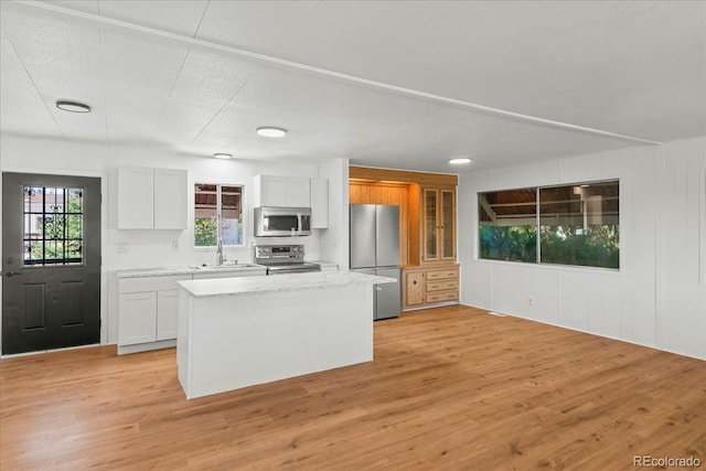 kitchen featuring a kitchen island, white cabinetry, stainless steel appliances, and light hardwood / wood-style flooring