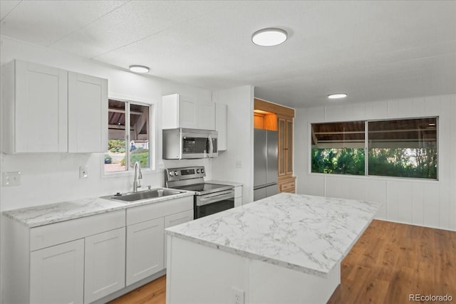 kitchen featuring appliances with stainless steel finishes, a center island, white cabinetry, and sink