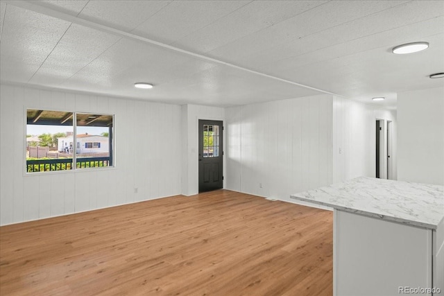 unfurnished living room featuring wood-type flooring and wooden walls