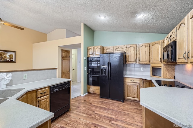 kitchen with dark wood-type flooring, vaulted ceiling, black appliances, and decorative backsplash