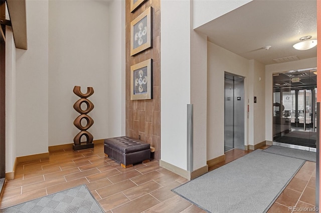 hall featuring elevator, baseboards, and wood finish floors