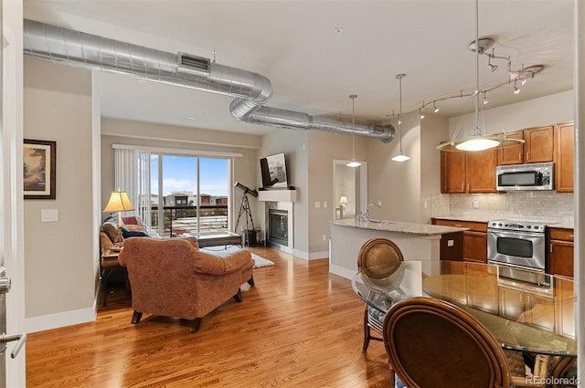 living room with a glass covered fireplace, light wood-style flooring, visible vents, and baseboards