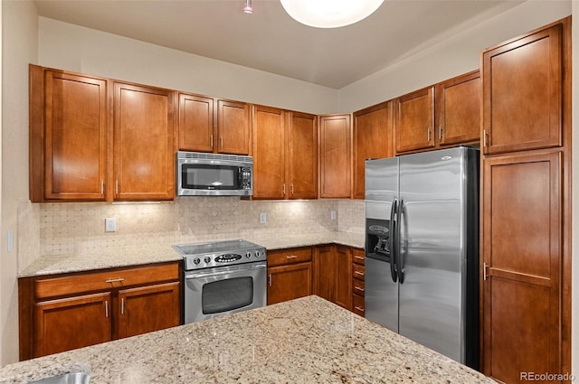 kitchen with brown cabinets, light stone countertops, tasteful backsplash, and stainless steel appliances