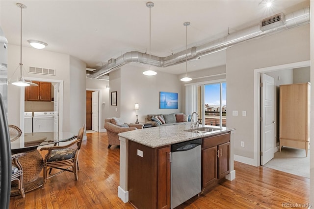 kitchen with washer and dryer, visible vents, light wood finished floors, a sink, and stainless steel dishwasher