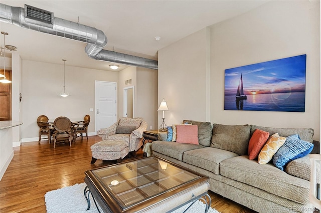 living room with visible vents, baseboards, and wood finished floors