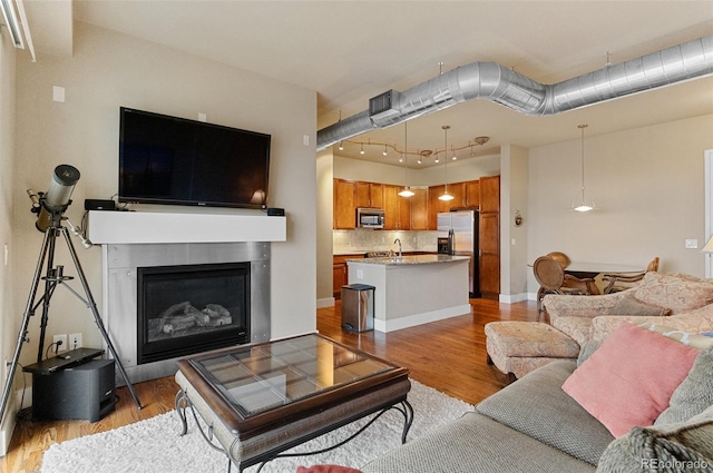 living area with visible vents, a glass covered fireplace, and light wood finished floors