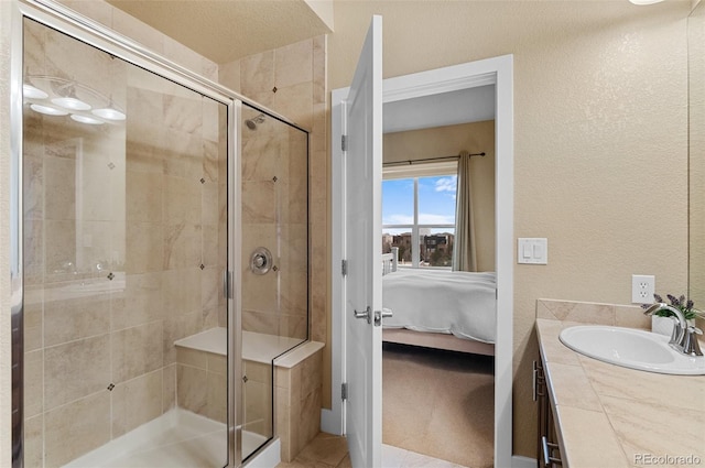 bathroom with vanity, a textured wall, a stall shower, and connected bathroom