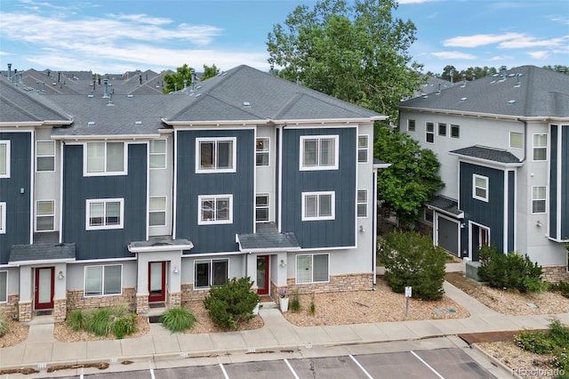 9300 E Florida Ave Unit 1202, Denver, CO 80247 - townhome / multi-family property featuring stone siding, board and batten siding, a shingled roof, and uncovered parking
