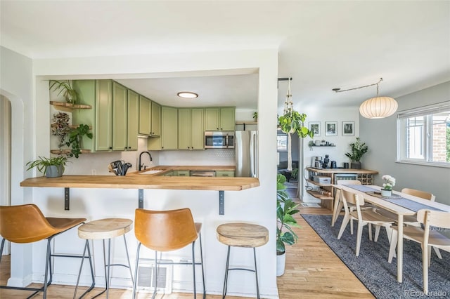 kitchen featuring green cabinets, appliances with stainless steel finishes, butcher block counters, and a sink