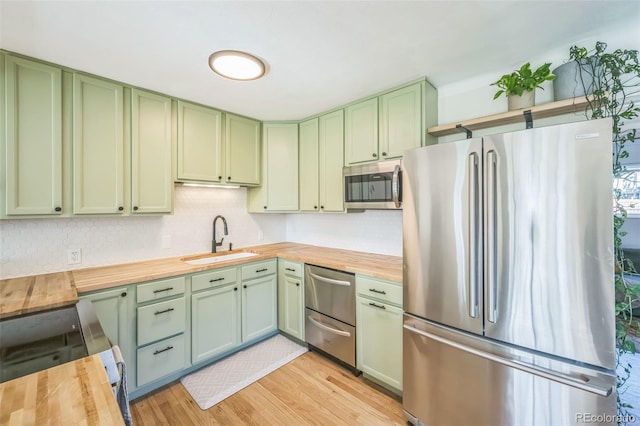 kitchen with green cabinets, stainless steel appliances, and butcher block countertops