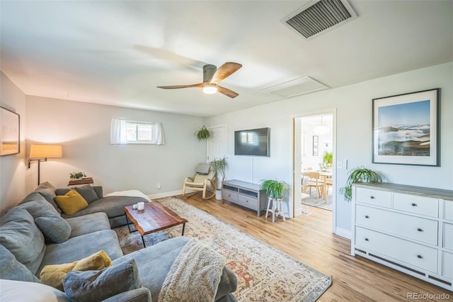 living room with light wood-style flooring, attic access, a ceiling fan, and baseboards