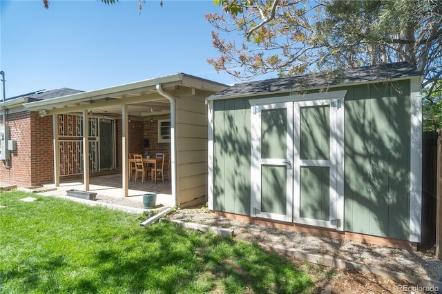 rear view of property featuring a storage shed, an outbuilding, a yard, and a patio