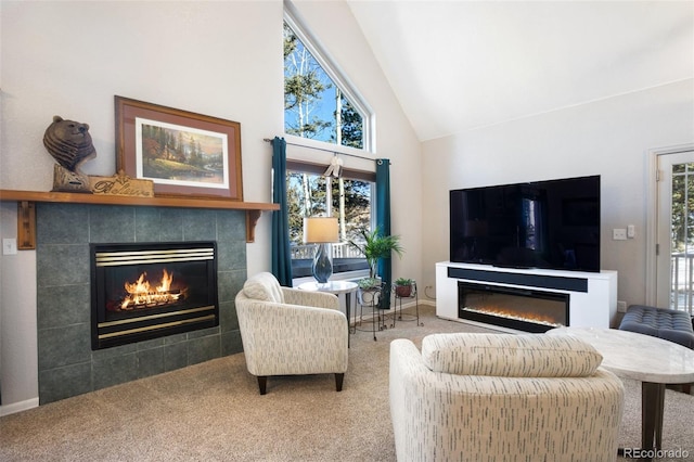 carpeted living room featuring a tile fireplace and high vaulted ceiling