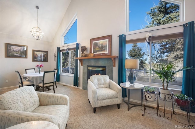 carpeted living room with high vaulted ceiling, a notable chandelier, and a tiled fireplace