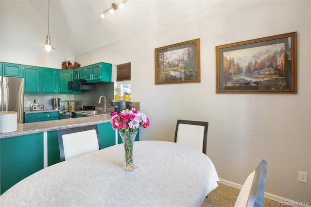 carpeted dining room with sink and vaulted ceiling