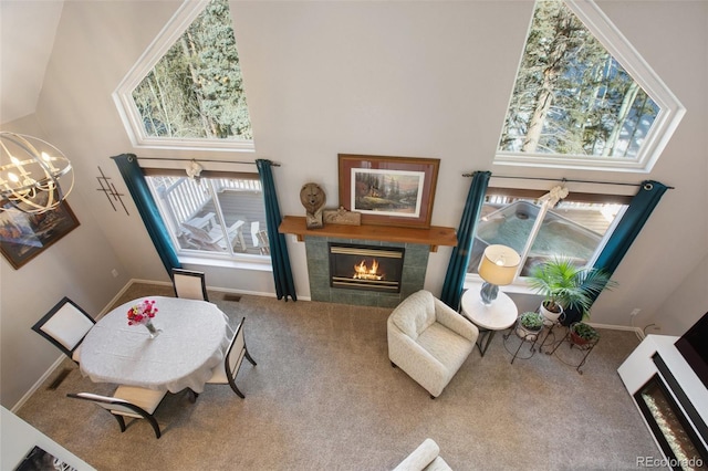 living area with a tiled fireplace, carpet floors, a high ceiling, and a notable chandelier