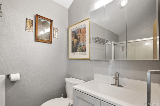 bathroom featuring toilet, lofted ceiling, and vanity