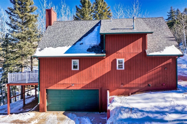 view of snowy exterior with a garage and a wooden deck