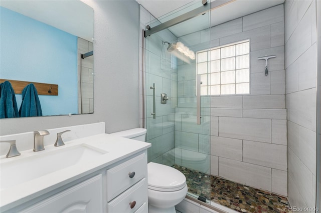 bathroom with walk in shower, vanity, and toilet