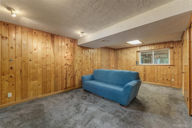 sitting room with a textured ceiling, wood walls, and carpet flooring