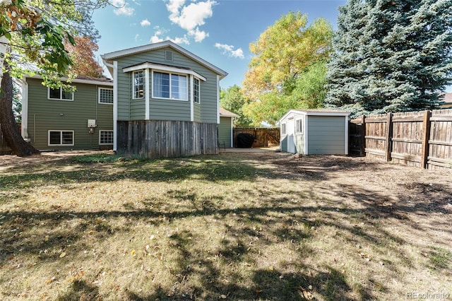 back of house featuring a storage shed and a yard