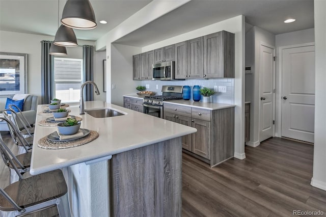 834 N Bently St, Watkins, CO 80137 - kitchen featuring stainless steel appliances, a sink, light countertops, dark wood finished floors, and a breakfast bar area