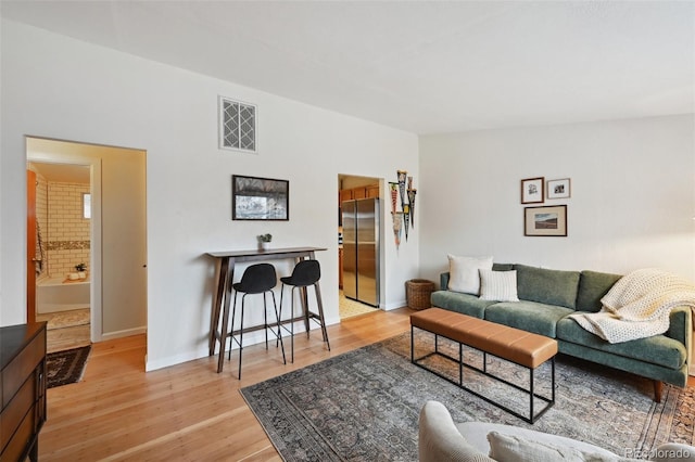 living room with light wood-type flooring, baseboards, and visible vents