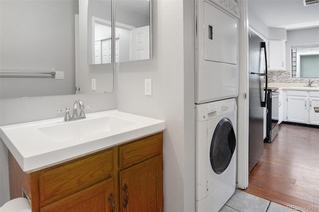 3600 S Pierce St Unit 2-201, Lakewood, CO 80235 - bathroom with stacked washing machine and dryer, vanity, and decorative backsplash