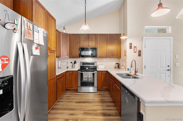 8779 S Kipling Way Unit 204, Littleton, CO 80127 - kitchen with appliances with stainless steel finishes, a sink, a peninsula, brown cabinets, and light wood finished floors